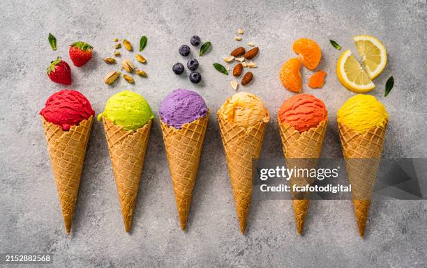 mehrfarbige eistüten mit fruchtgeschmack in einer reihe von oben aufgenommen - eisbecher stock-fotos und bilder