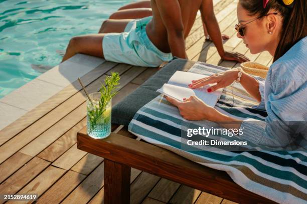 ragazza leggendo un libro con la piscina - bordo piscina foto e immagini stock
