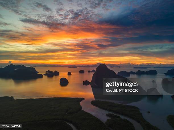 aerial view of phang nga bay with the waterway leading into the sea and surrounding green mountains under the sunrise. - beach aerial sunset stock pictures, royalty-free photos & images
