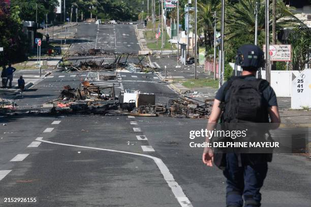 Police patrol a street blocked by debris and burnt out items following overnight unrest in the Magenta district of Noumea, France's Pacific territory...