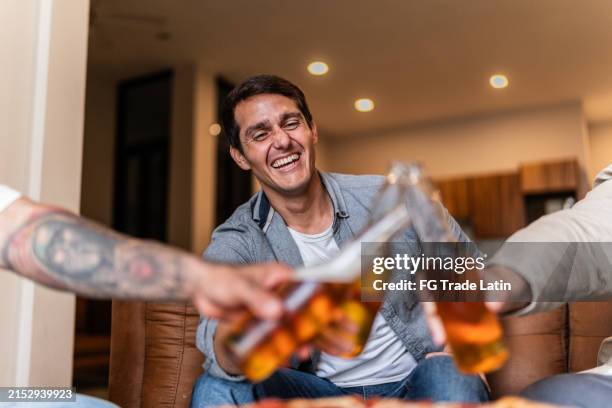 friends talking and toasting beer at home - beer drinking home stock pictures, royalty-free photos & images
