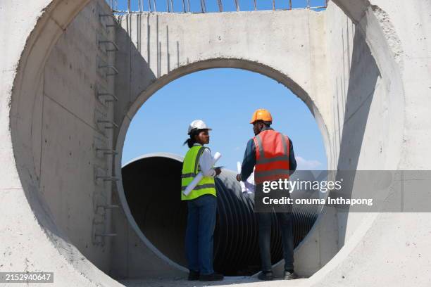 back two construction engineers discussing help create a plan with a blueprint home building at the construction site, rectangular concrete infrastructure of drain system. - engineer-team-cutout stock pictures, royalty-free photos & images