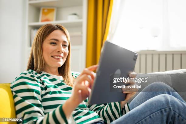 young woman using digital tablet at home - tablet pc stock-fotos und bilder