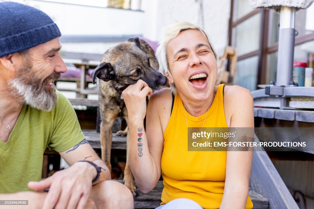 Dog is licking woman´s face while pat owner is watching the situation