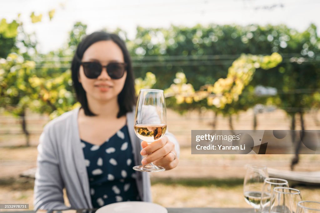 Asian young girl raising a wineglass toward camera-selective focus