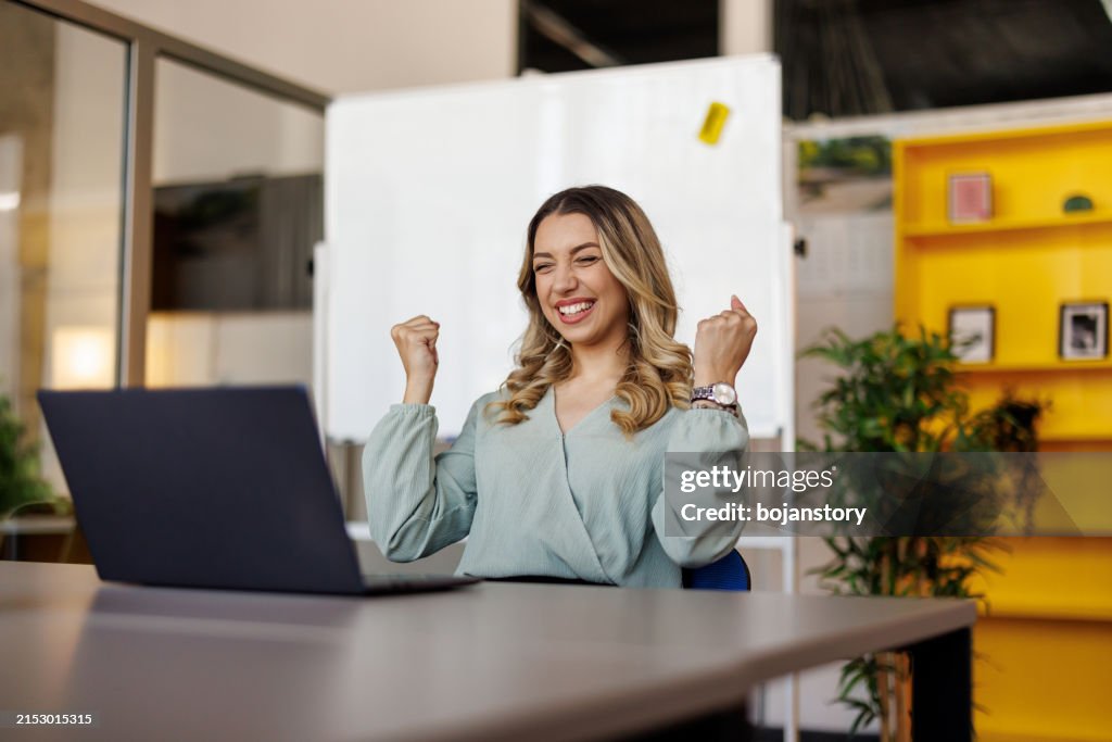 Excited businesswoman triumphing with fist up in office