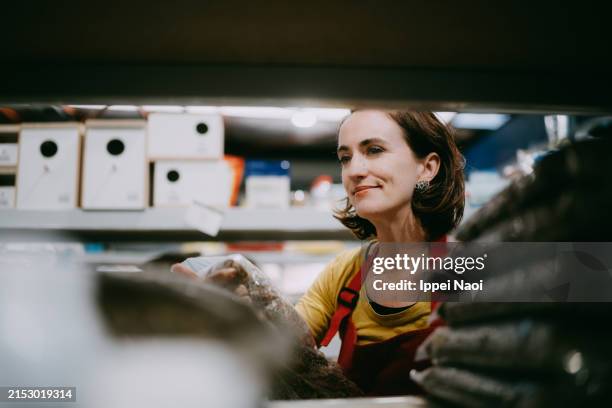 woman working in store restocking retail display - grocery store worker restocking shelves stock pictures, royalty-free photos & images
