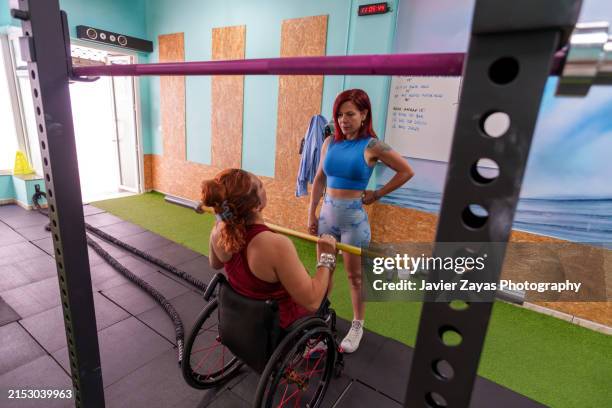disabled woman exercising with his personal trainer in a gym - paralysis stock pictures, royalty-free photos & images