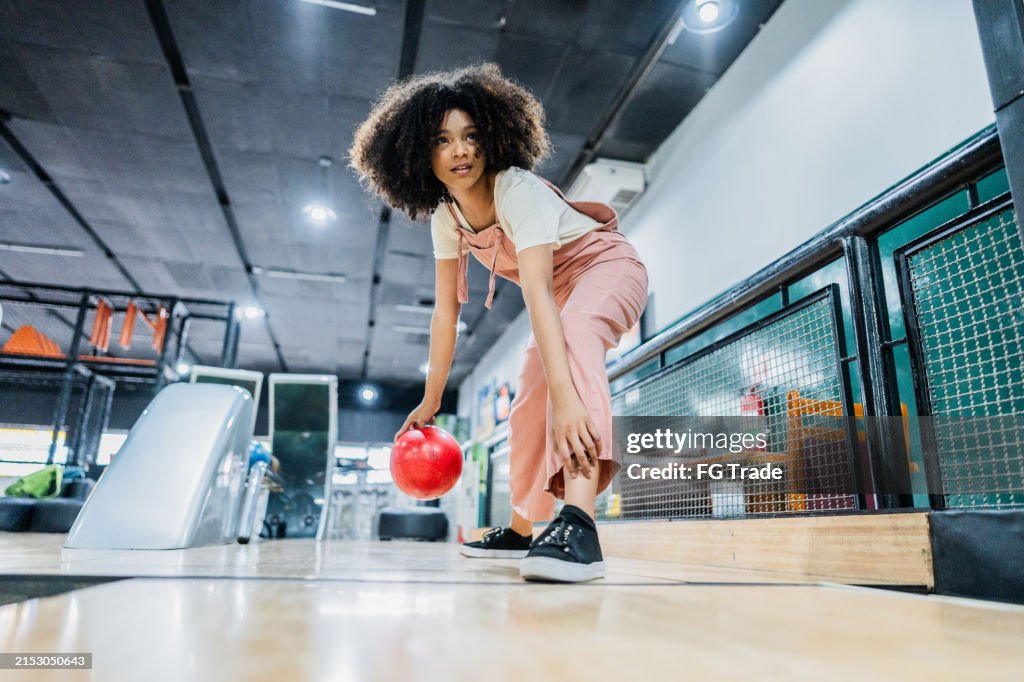 Young woman playing bowling on a bowling alley