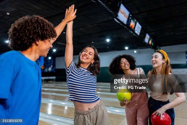 friends high-fiving on a bowling alley - bowling stock pictures, royalty-free photos & images