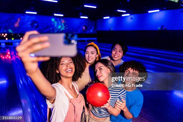 freunde, die ein selfie machen oder auf einer party auf einer bowlingbahn filmen - bowling stock-fotos und bilder