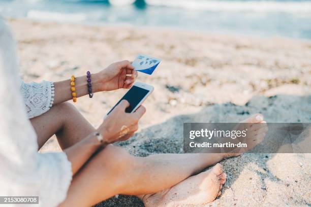 frau am strand online einkaufen mit kreditkarte - geld verheizen stock-fotos und bilder
