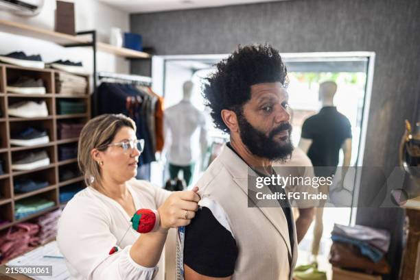 tailor measuring a mature man groom for new suit at clothing store - try on stock pictures, royalty-free photos & images