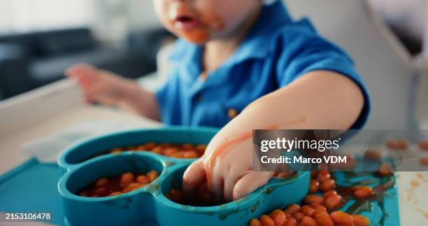 bebé, manos y desorden en la silla con comida para la hora de comer o apetito, autoalimentarse y aprender a comer con experiencia sensorial. niño pequeño, frijoles y desarrollo del crecimiento o hito y nutrición. - judios fotografías e imágenes de stock