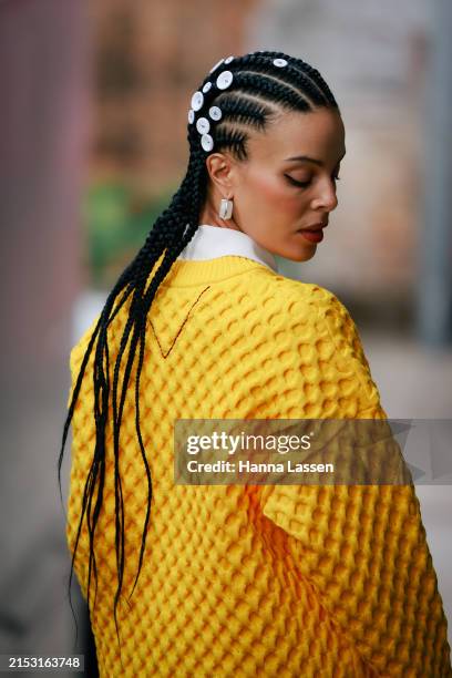 Fleur Egan wearing buttons on her hair, yellow jumper, green and blue mixed colour maxi split skirt, white boots and green and white bag during...