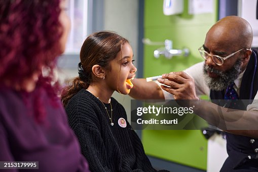 Male paediatrician checking child's throat Male paediatrician checking child's throat