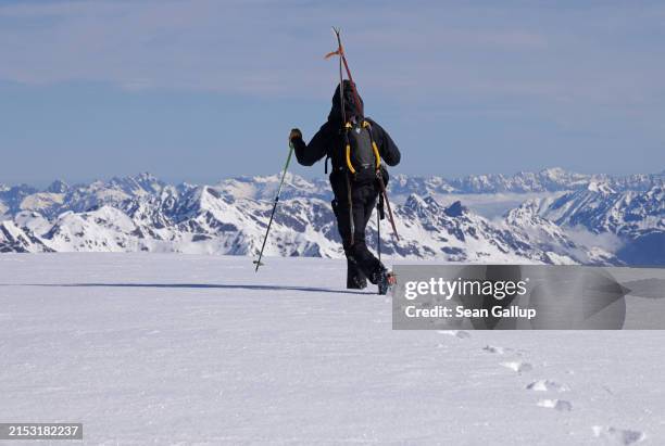 Ski tourer walks across Weissseespitze peak in the Ötztal Alps as snow-covered mountains in Austria stretch behind on May 10, 2024 above Kaunertal,...