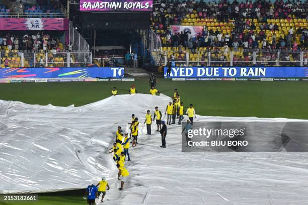 Ground staff cover the field as rain delays the start of the Indian Premier League Twenty20 cricket match between Rajasthan Royals and Kolkata Knight...