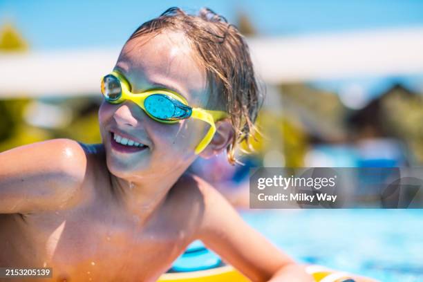 joyful child boy wearing yellow swimming goggles, smiling and enjoying a sunny day at the pool. - buitenbad stockfoto's en -beelden
