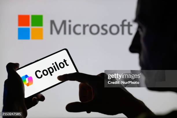 The Copilot logo is being displayed on a smartphone with Microsoft visible in the background in this photo illustration in Brussels, Belgium, on May...