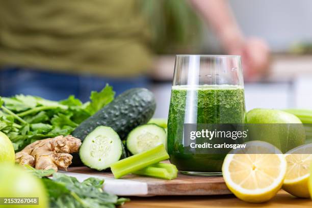 glass of detox juice surrounded by fruits and vegetables on a kitchen table - selderij stockfoto's en -beelden