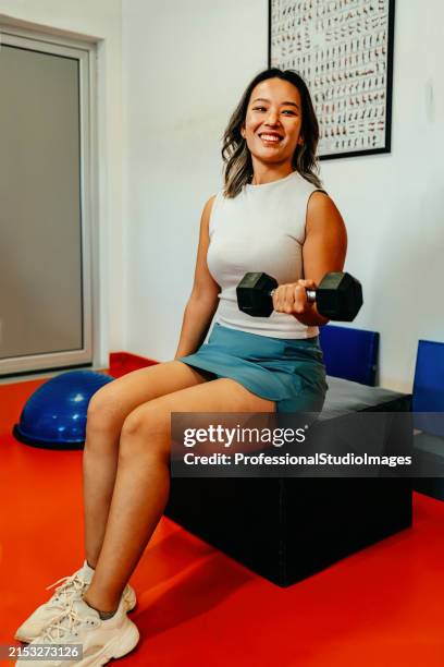 a woman sitting on a box holding a dumbbell - ankle weights stock pictures, royalty-free photos & images