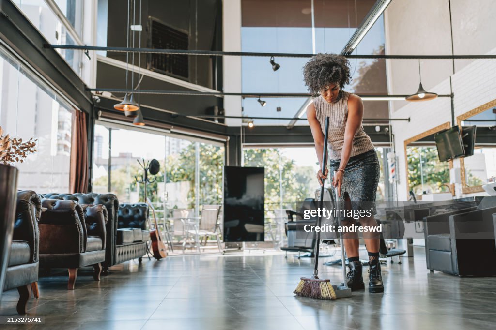 Mujer limpiando el suelo de la barbería con una escoba