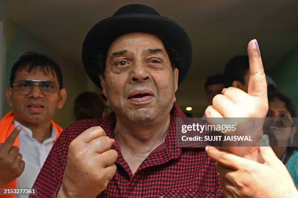 Bollywood actor Dharmendra displays his ink marked finger after casting ballot at a polling station during the fifth phase of voting in India's...