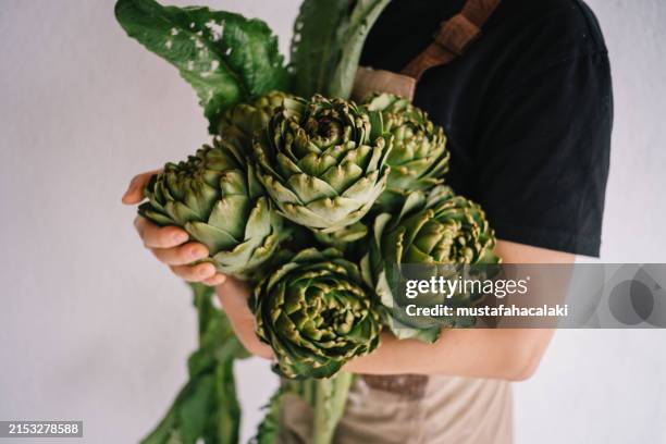 young woman is holding artichokes - artichoke stock pictures, royalty-free photos & images