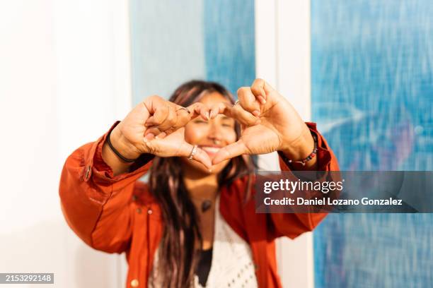 latin woman gesturing heart shape with hands - gratidão imagens e fotografias de stock