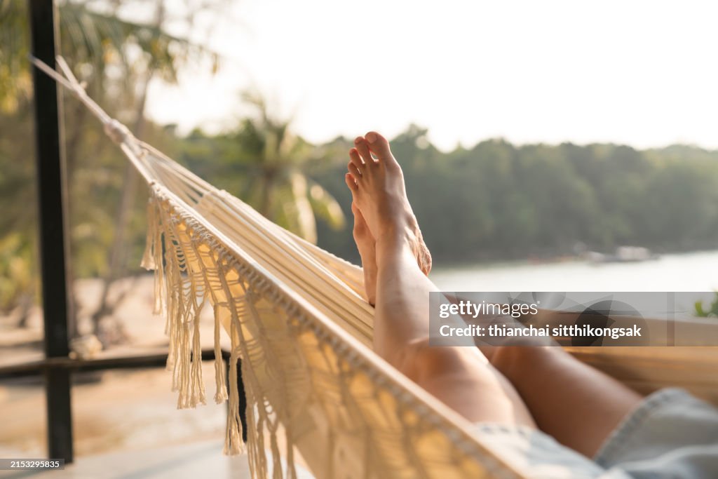 Woman relaxing on hammock, feet view