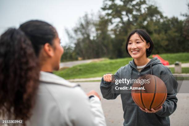 hispanic female and asian female fist pump - streetball stock pictures, royalty-free photos & images