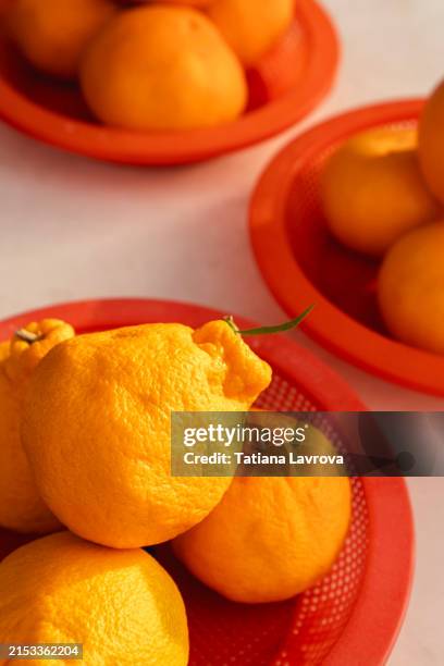 bright oranges in red plastic baskets on white table in daylight. variety of beautiful juicy orange and yellow tangerines at a local street vendor. - complejo vitamínico b fotografías e imágenes de stock