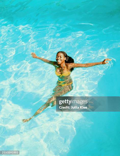 young woman in swimming pool smiling - black woman floating water stock pictures, royalty-free photos & images