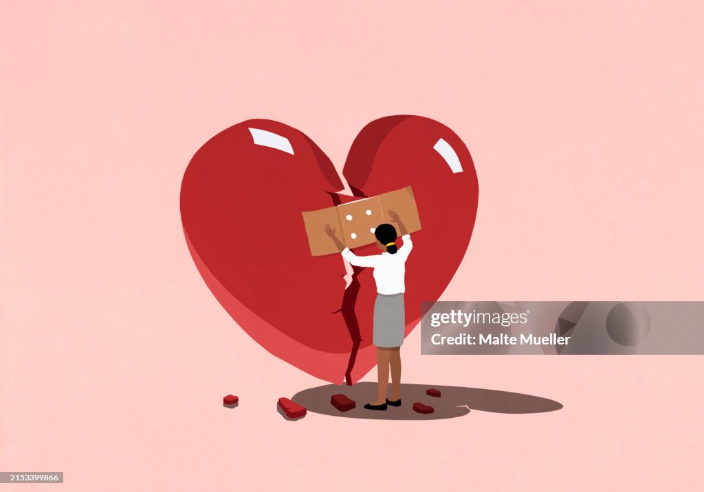 Woman placing bandage over large broken heart on pink background