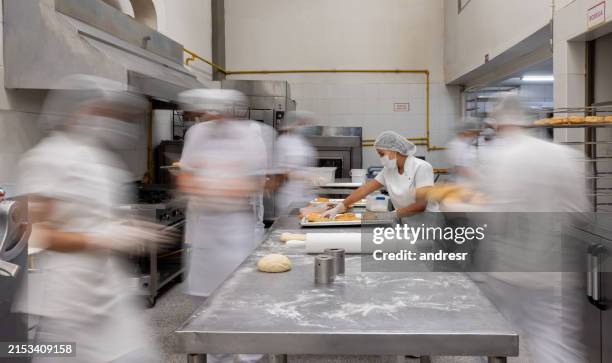 empleado que trabaja en una concurrida fábrica de donas - acero inoxidable fotografías e imágenes de stock