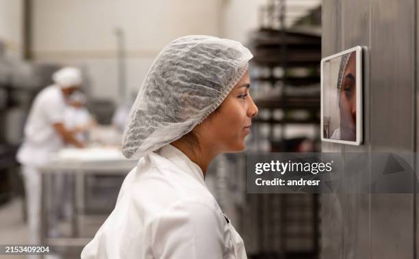 worker and using facial recognition camera to start his shift at a factory - rede de cabelo imagens e fotografias de stock