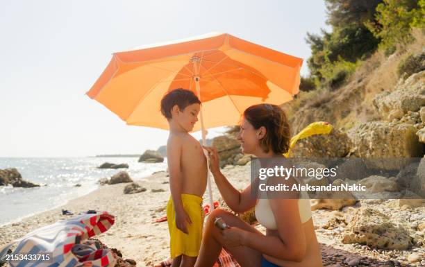 applying sunscreen while at the beach - sunburned woman stock pictures, royalty-free photos & images