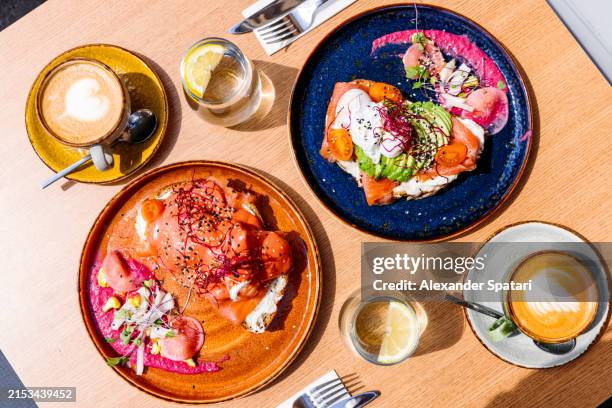 avocado toast and eggs benedict served for brunch at the cafe, directly above view - stylisme culinaire photos et images de collection