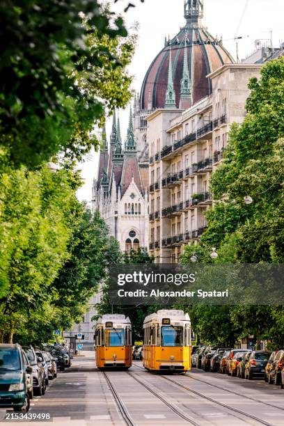 yellow trams on the streets of budapest with hungarian parliament building in background, hungary - budapest stock pictures, royalty-free photos & images