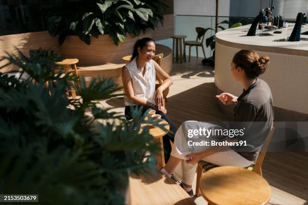 two friends indulge in meaningful conversation at cafe - mannerism stock pictures, royalty-free photos & images