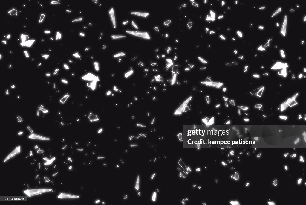 Broken Glass on Black Background shows the abstract texture of the shattered glass in great detail. The image is perfect for use in backgrounds, textures, or abstract art projects.