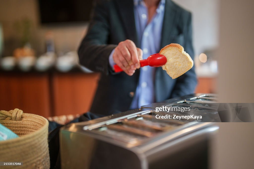 Homme utilisant un grille-pain dans la salle de petit-déjeuner en libre-service de l’hôtel.