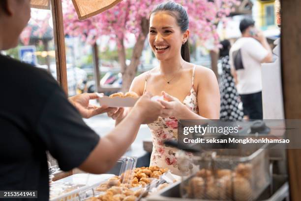 woman eating street food at market - korean street food stock pictures, royalty-free photos & images