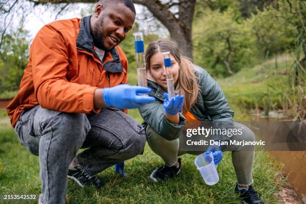 young scientists doing research in nature taking a water sample from a lake - biologe stock-fotos und bilder