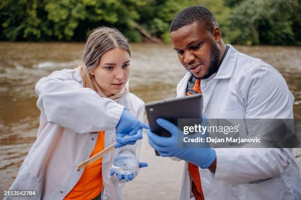 young scientists doing research in nature taking sample of water from a river - riverbank stock pictures, royalty-free photos & images