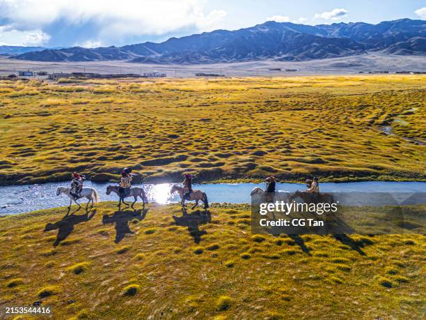 group of kazakh eagle hunters riding horses along river bayan olgii, west mongolia - mongoolse etniciteit stockfoto's en -beelden