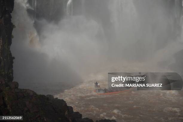 Tourists enjoy a boat ride under the San Martin waterfall, part of the Iguazu Falls waterfall system on the Iguazu River at Iguazu National Park near...