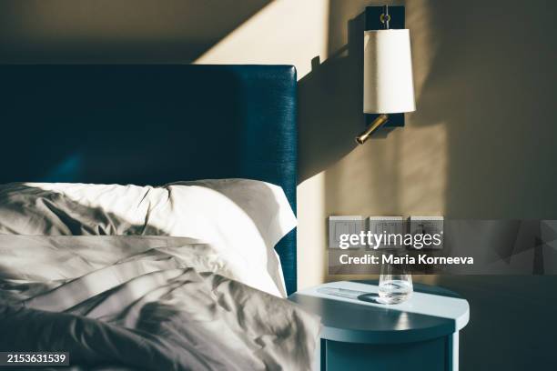 glass of water on bedside table. - manta-ropa-de-cama fotografías e imágenes de stock