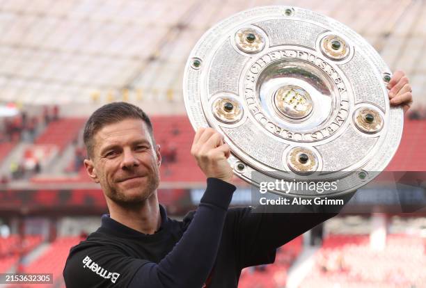 Head coach Xabi Alonso of Bayer Leverkusen celebrates with the Meisterschale of Bundesliga trophy after their team's victory during the Bundesliga...